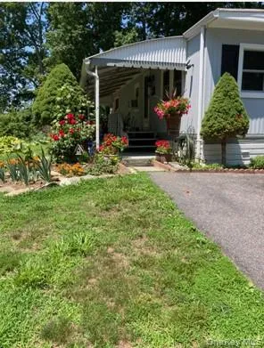 a view of a house that has a bunch of plants and large trees