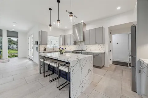 a large kitchen with kitchen island a chandelier a sink stainless steel appliances and cabinets