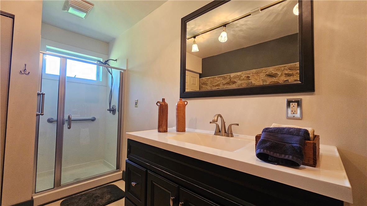 585 Buttermilk Road Hellertown, PA 18055 - Photo 24 of 82 A sleek vanity with a wide mirror complements the modern glass-enclosed shower.