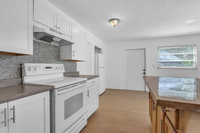 a kitchen with cabinets appliances and wooden floor