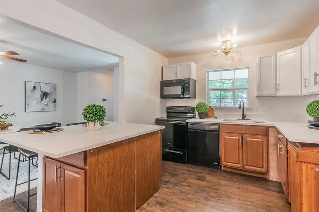 a kitchen with stainless steel appliances kitchen island a table chairs sink and stove top oven