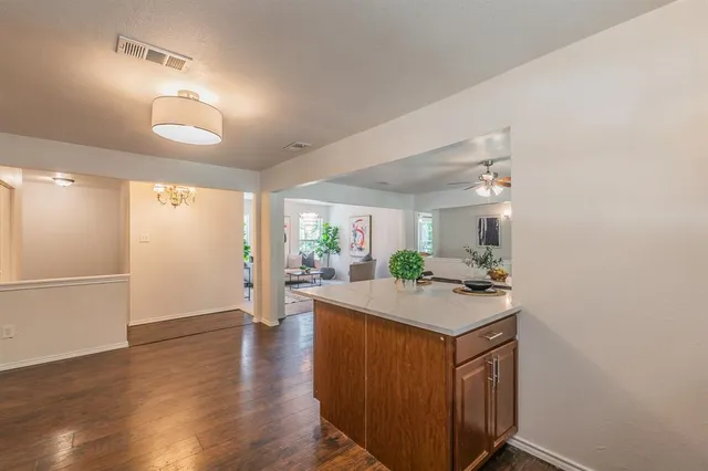 a room with kitchen island a sink and wooden floor
