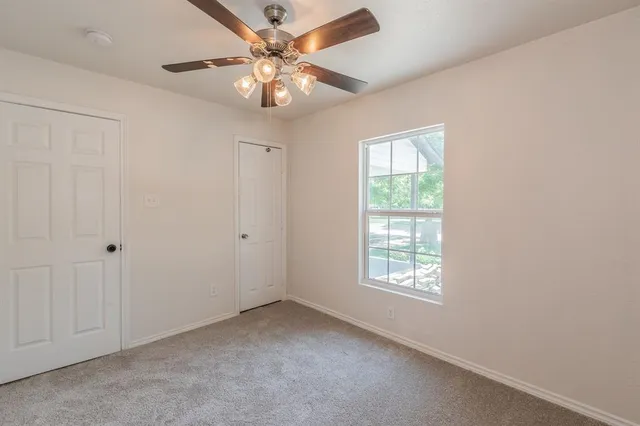 an empty room with windows and fan