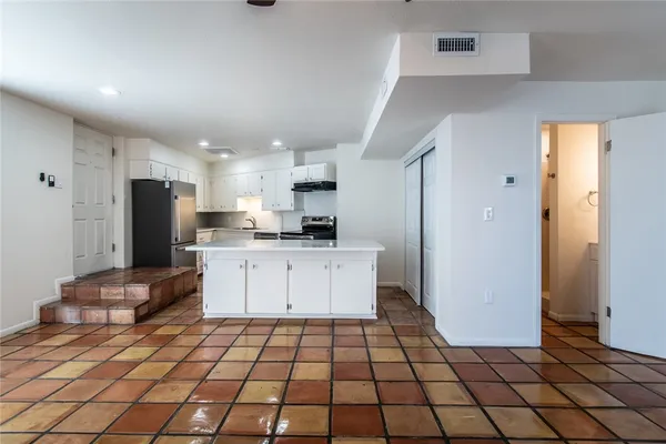 a kitchen with a refrigerator and white cabinets