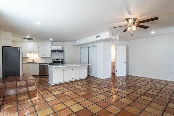a kitchen with stainless steel appliances kitchen island granite countertop a refrigerator and a stove top oven