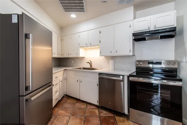 a kitchen with cabinets stainless steel appliances and a sink