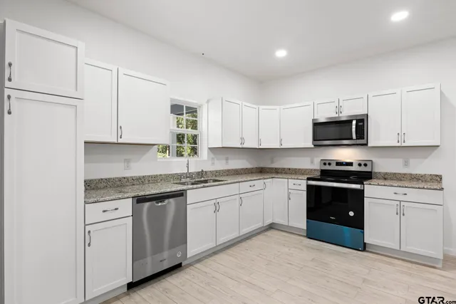 a kitchen with granite countertop white cabinets and stainless steel appliances