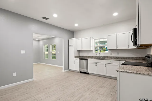 a kitchen with granite countertop white cabinets and white appliances