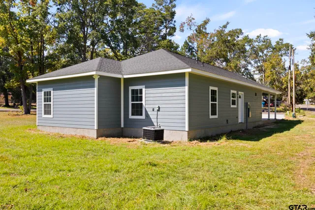 a front view of house with yard and trees in the background