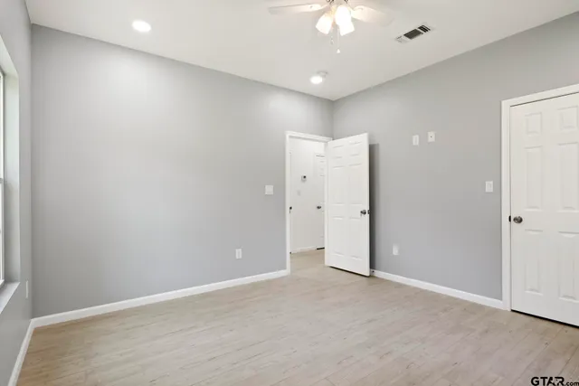 an empty room with a ceiling fan and closet area
