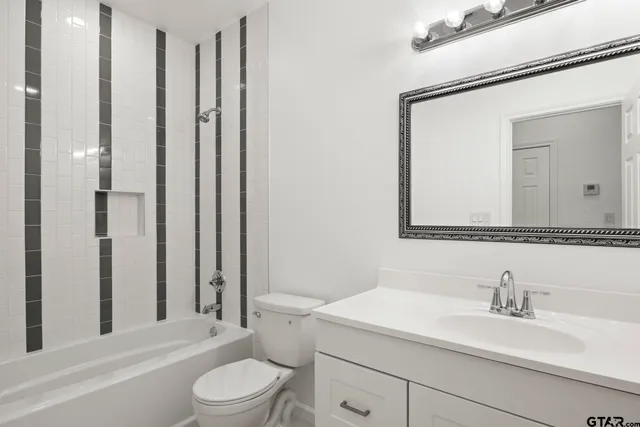 a bathroom with a granite countertop sink vanity mirror and toilet