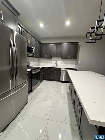 a kitchen with stainless steel appliances granite countertop a sink and a refrigerator