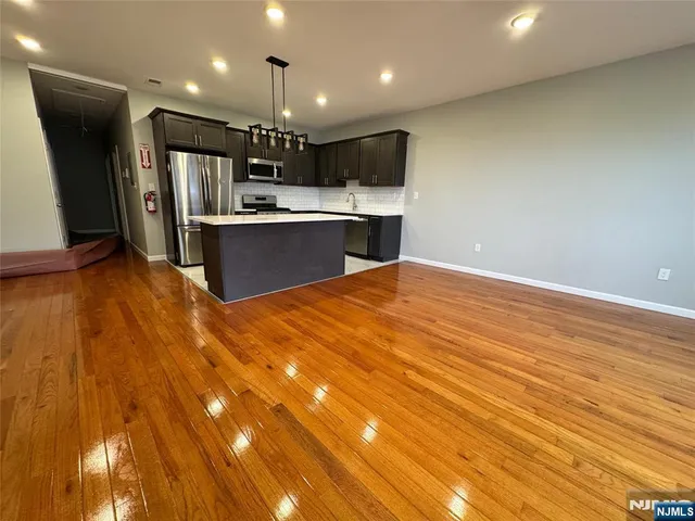 a view of kitchen with kitchen island wooden floor center island and stainless steel appliances