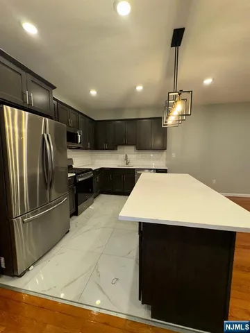a kitchen with stainless steel appliances a refrigerator and a wooden floor