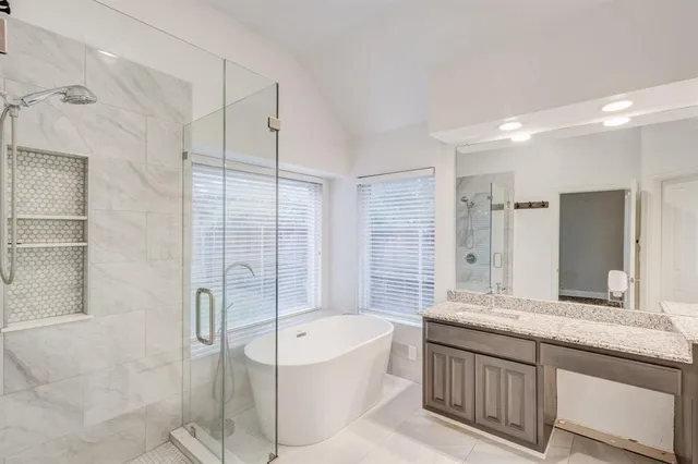 a bathroom with a granite countertop bathtub sink vanity and mirror