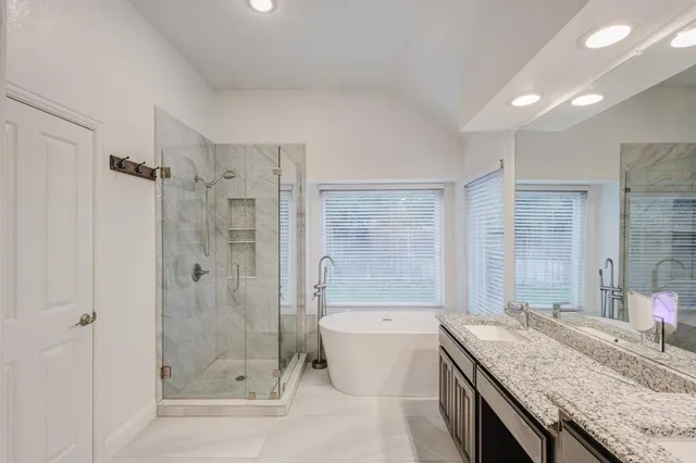 a bathroom with a granite countertop sink a mirror a bathtub and shower