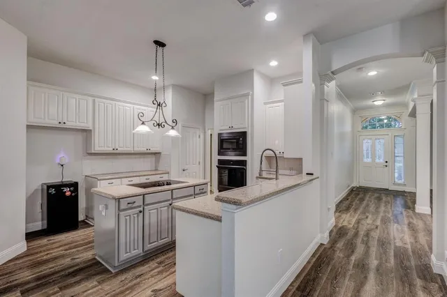 a kitchen with stainless steel appliances a stove top oven a sink dishwasher and a refrigerator with wooden floor