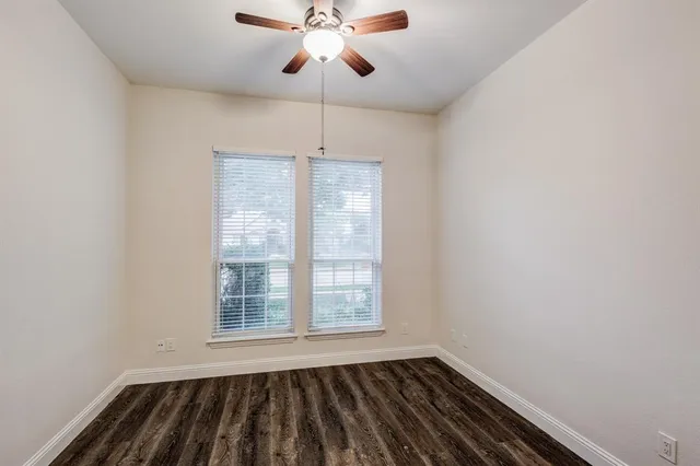 an empty room with windows and fan