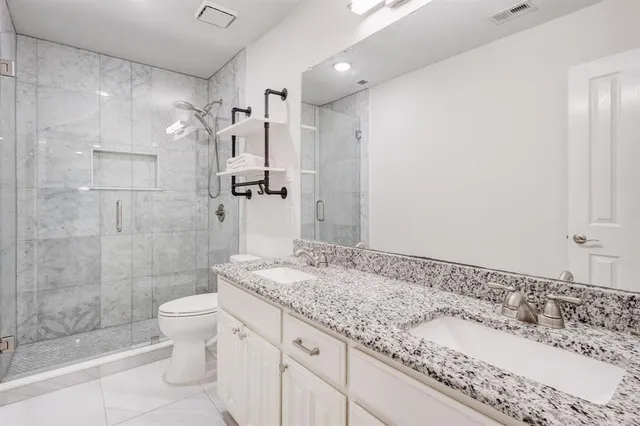 a bathroom with a granite countertop sink a toilet and shower