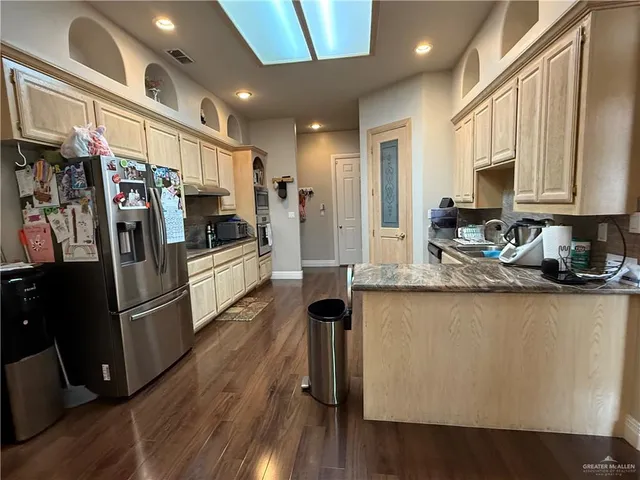 a kitchen with stainless steel appliances granite countertop a refrigerator a stove and a sink