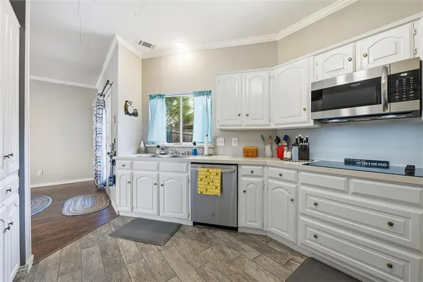 a kitchen with stainless steel appliances white cabinets a sink and a stove