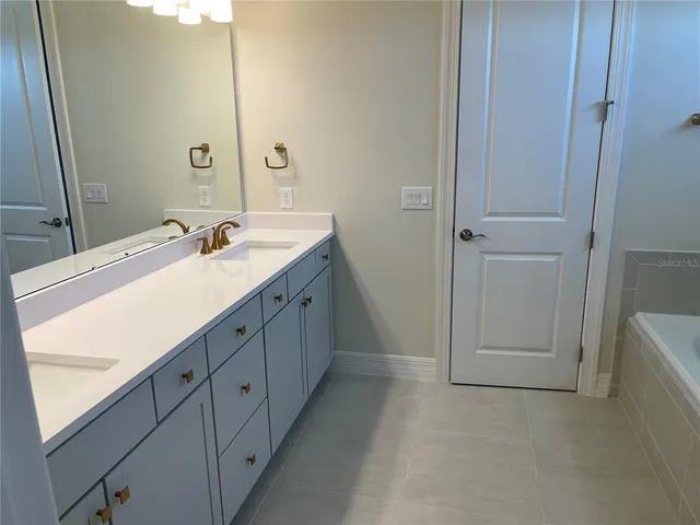 a spacious bathroom with a double vanity sink a mirror and a bathtub