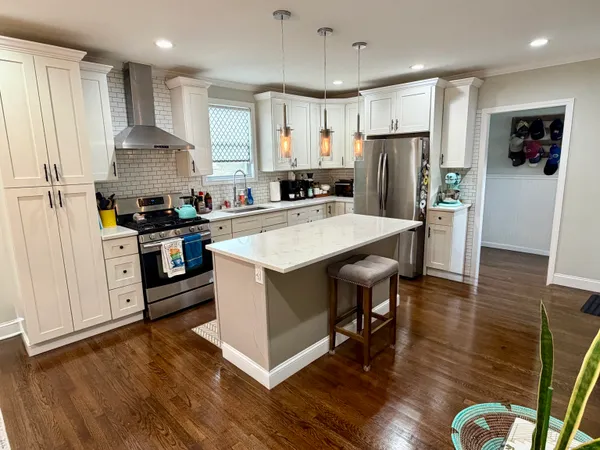 a kitchen with stainless steel appliances granite countertop a refrigerator a stove top oven a sink dishwasher and white cabinets with wooden floor