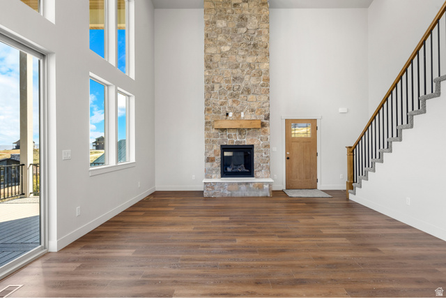 1159 North Broad Hollow Road Garden City, UT 84028 - Photo 4 of 55 Spacious living area featuring a floor-to-ceiling stone fireplace, wood-finish flooring, and a multi-level window arrangement