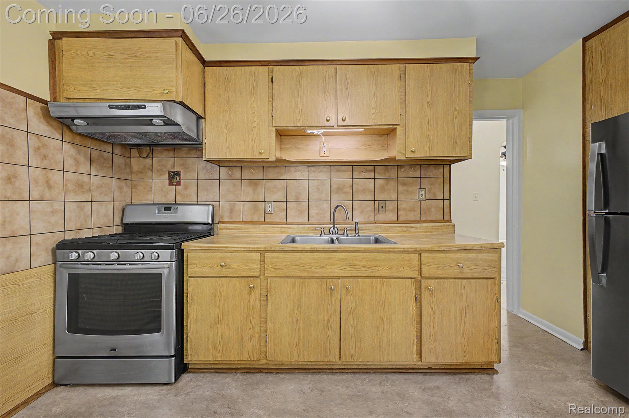 2216 Banner Street Dearborn, MI 48124 - Photo 18 of 34 Kitchen featuring wood-finish cabinetry, a double basin stainless steel sink, and a stainless steel gas range with coordinating range hood