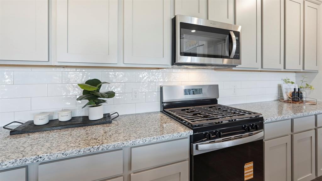 4197 Waldron Trail Forney, TX 75126 - Photo 6 of 25 Kitchen featuring a gas range, stainless steel microwave, white subway tile backsplash, light-toned countertops, and shaker-style cabinetry