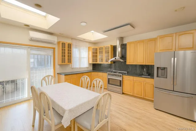 a kitchen with stainless steel appliances granite countertop a refrigerator a sink a stove and white cabinets with wooden floor