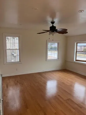 a view of an empty room with wooden floor and a window