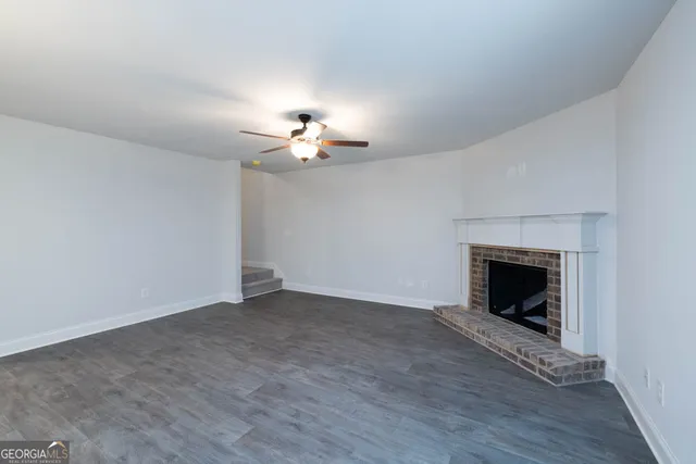 a view of an empty room with wooden floor and fireplace