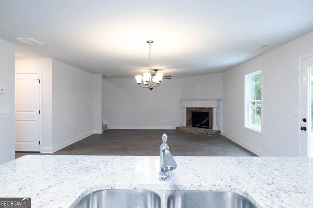 a view of a livingroom with a fireplace a chandelier fan and windows