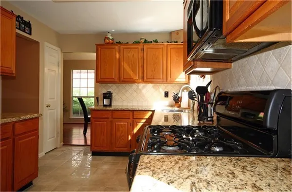 a kitchen with stainless steel appliances granite countertop a stove a sink and a microwave