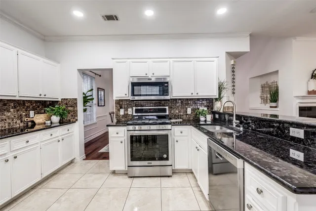 a kitchen with stainless steel appliances granite countertop a stove a sink and a microwave