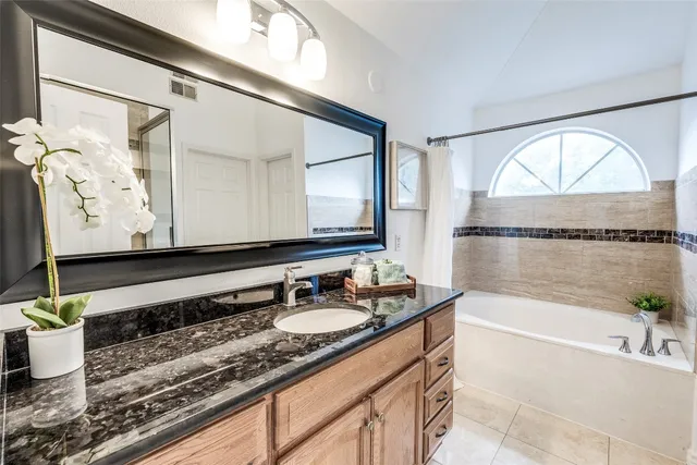 a bathroom with a granite countertop sink mirror and bathtub