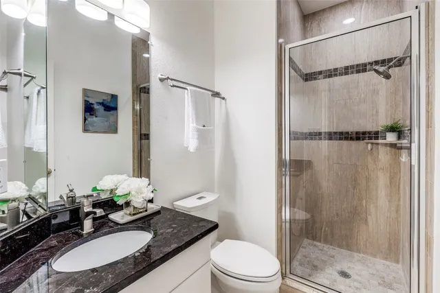 a bathroom with a granite countertop sink toilet and shower