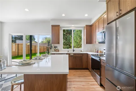 a kitchen with stainless steel appliances granite countertop a refrigerator a sink a stove and a refrigerator
