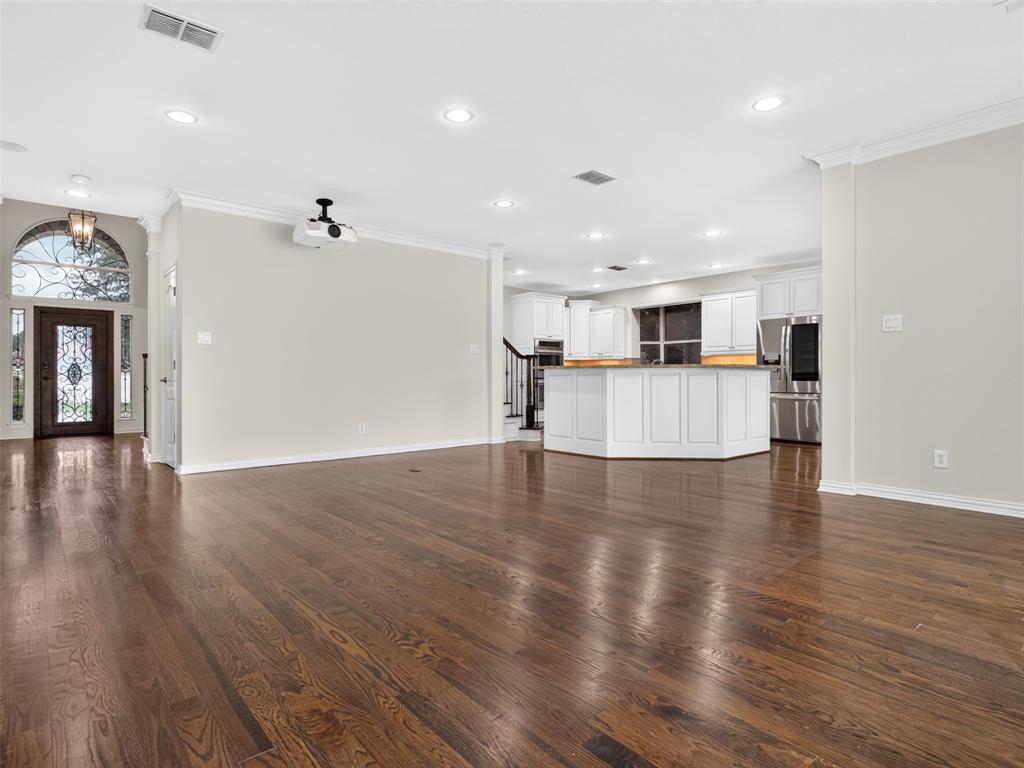 6809 Cedar Ridge Court Plano, TX 75093 - Photo 14 of 38 Wood-finish flooring throughout, recessed ceiling lighting, a decorative glass-paneled entry door with an arched transom, white kitchen cabinetry, and stainless steel appliances