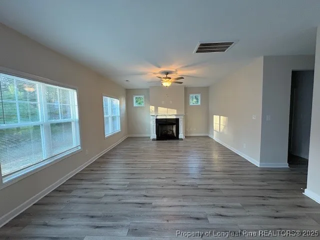 a view of an empty room with window and wooden floor