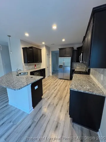 a large kitchen with stainless steel appliances kitchen island granite countertop a large counter top and wooden floors