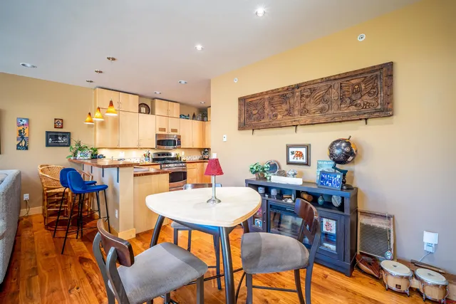 a kitchen with stainless steel appliances a dining table chairs and a refrigerator a sink with wooden floor