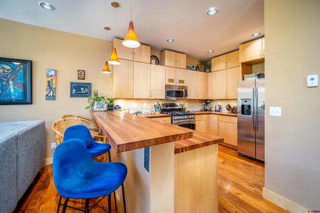 a kitchen with stainless steel appliances kitchen island granite countertop a refrigerator a sink a stove and a refrigerator