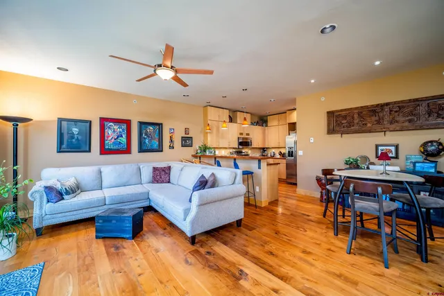 a living room with furniture kitchen view and a wooden floor