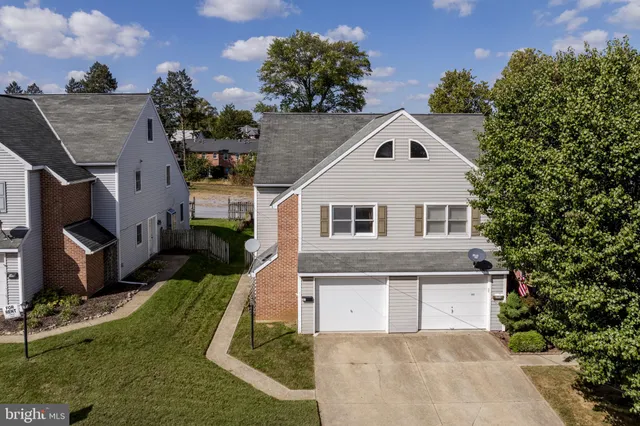 a view of a white house next to a yard with potted plants