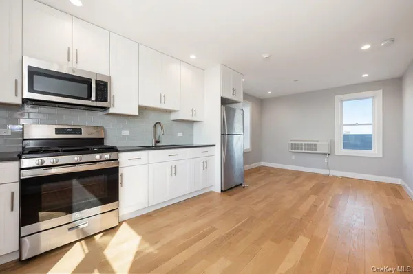 a kitchen with stainless steel appliances granite countertop a stove a microwave and white cabinets