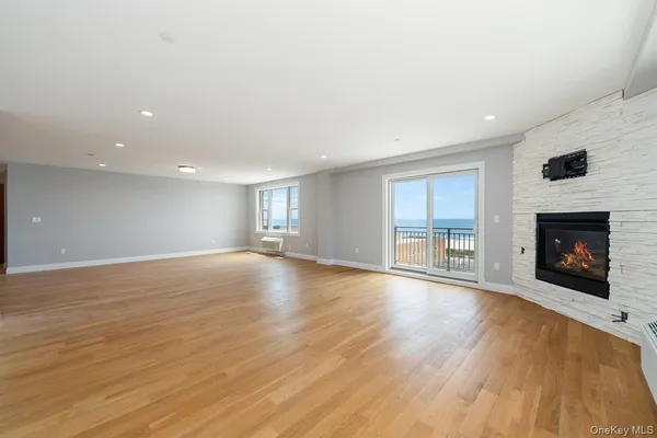 an empty room with wooden floor fireplace and windows