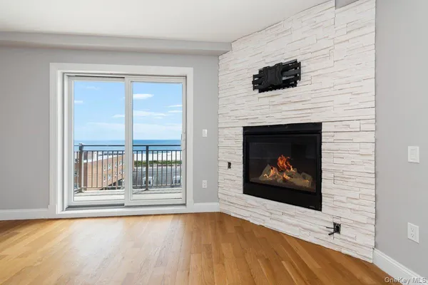 a view of an empty room with wooden floor fireplace and a window