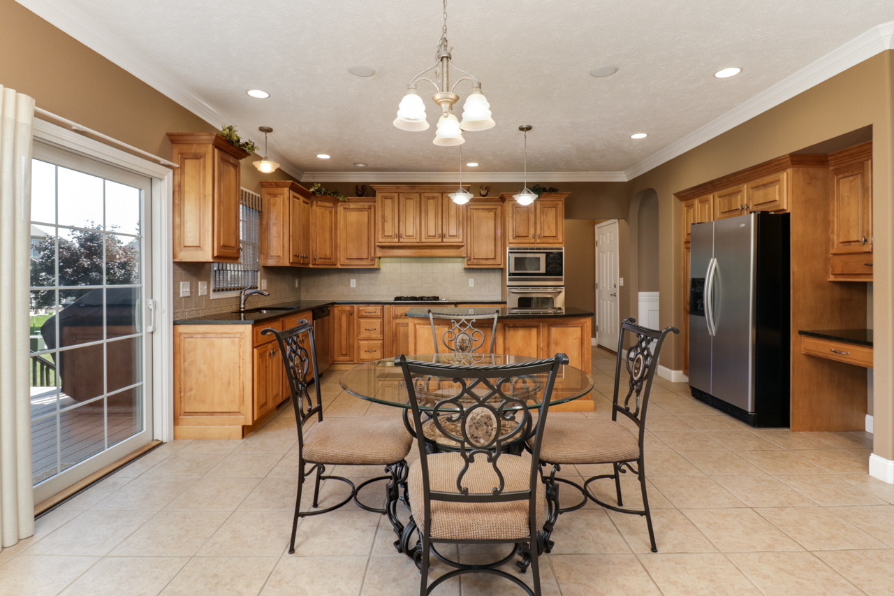 4012 Rockledge Road Bloomington, IL 61705 - Photo 17 of 63 a kitchen with stainless steel appliances granite countertop a stove top oven a refrigerator a sink and a dining table with chairs